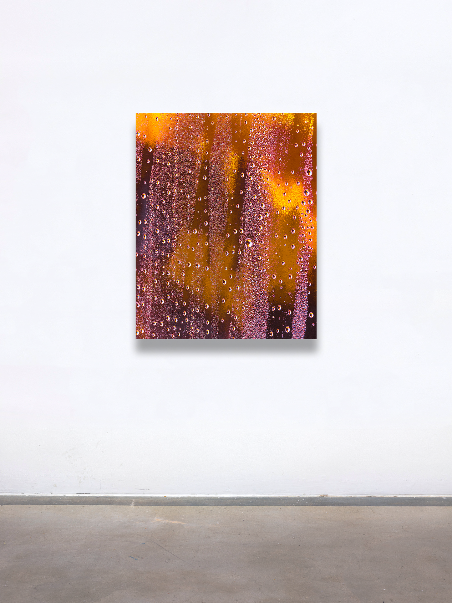 A graduate artist in the UK captures a close-up of condensation droplets on a glass surface, where vibrant orange and yellow lighting create an abstract pattern. This mesmerizing piece is part of the graduate artworks for sale by The Graduate Gallery.