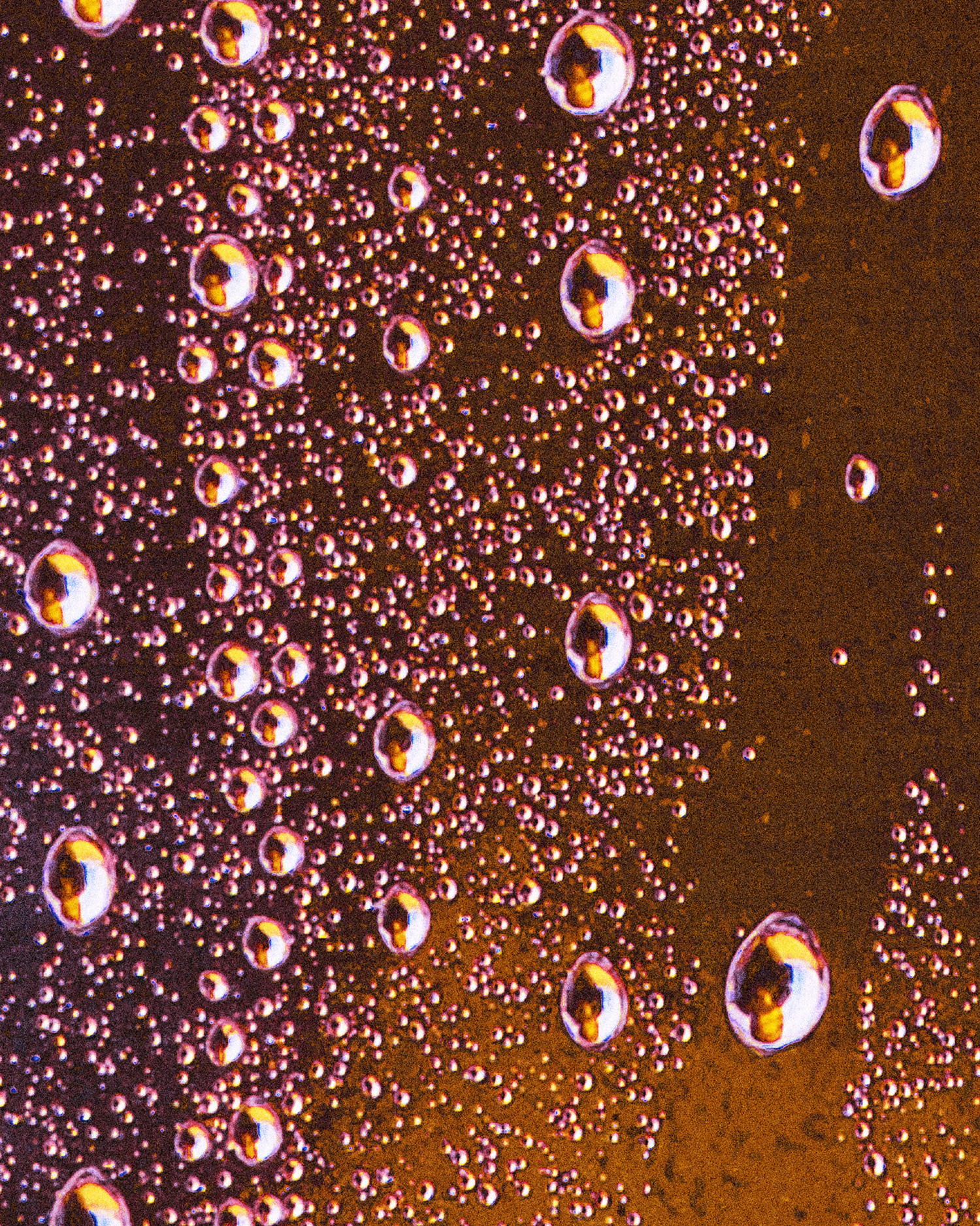 A graduate artist in the UK captures a close-up of condensation droplets on a glass surface, where vibrant orange and yellow lighting create an abstract pattern. This mesmerizing piece is part of the graduate artworks for sale by The Graduate Gallery.