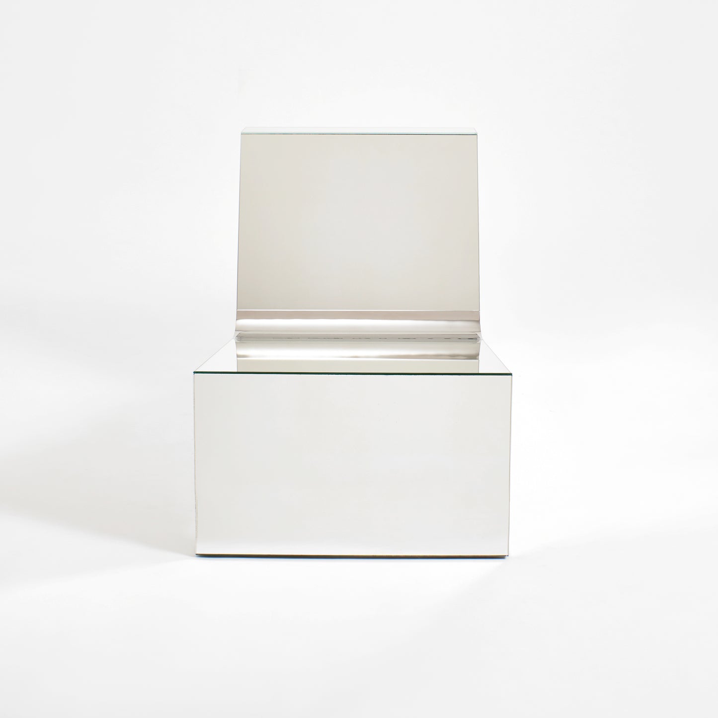 Discover a modern chair with a minimalist design, featuring a reflective mirror surface. Its angular shape creates a geometric aesthetic, set against a plain white background. This stunning piece of furniture is available for sale by The Graduate Gallery.
