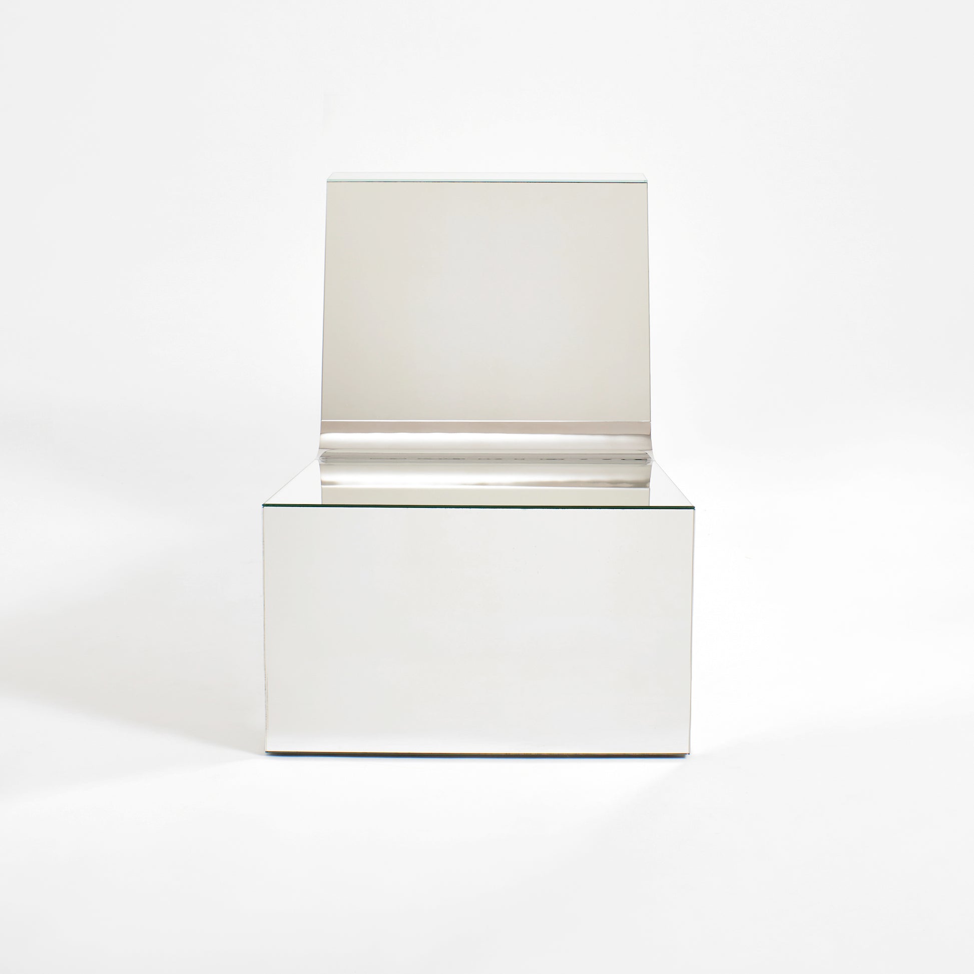 Discover a modern chair with a minimalist design, featuring a reflective mirror surface. Its angular shape creates a geometric aesthetic, set against a plain white background. This stunning piece of furniture is available for sale by The Graduate Gallery.