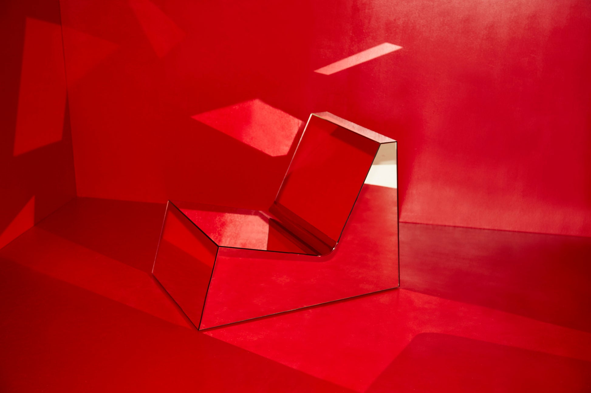 Discover a modern chair with a minimalist design, featuring a reflective mirror surface. Its angular shape creates a geometric aesthetic, set against a plain white background. This stunning piece of furniture is available for sale by The Graduate Gallery.