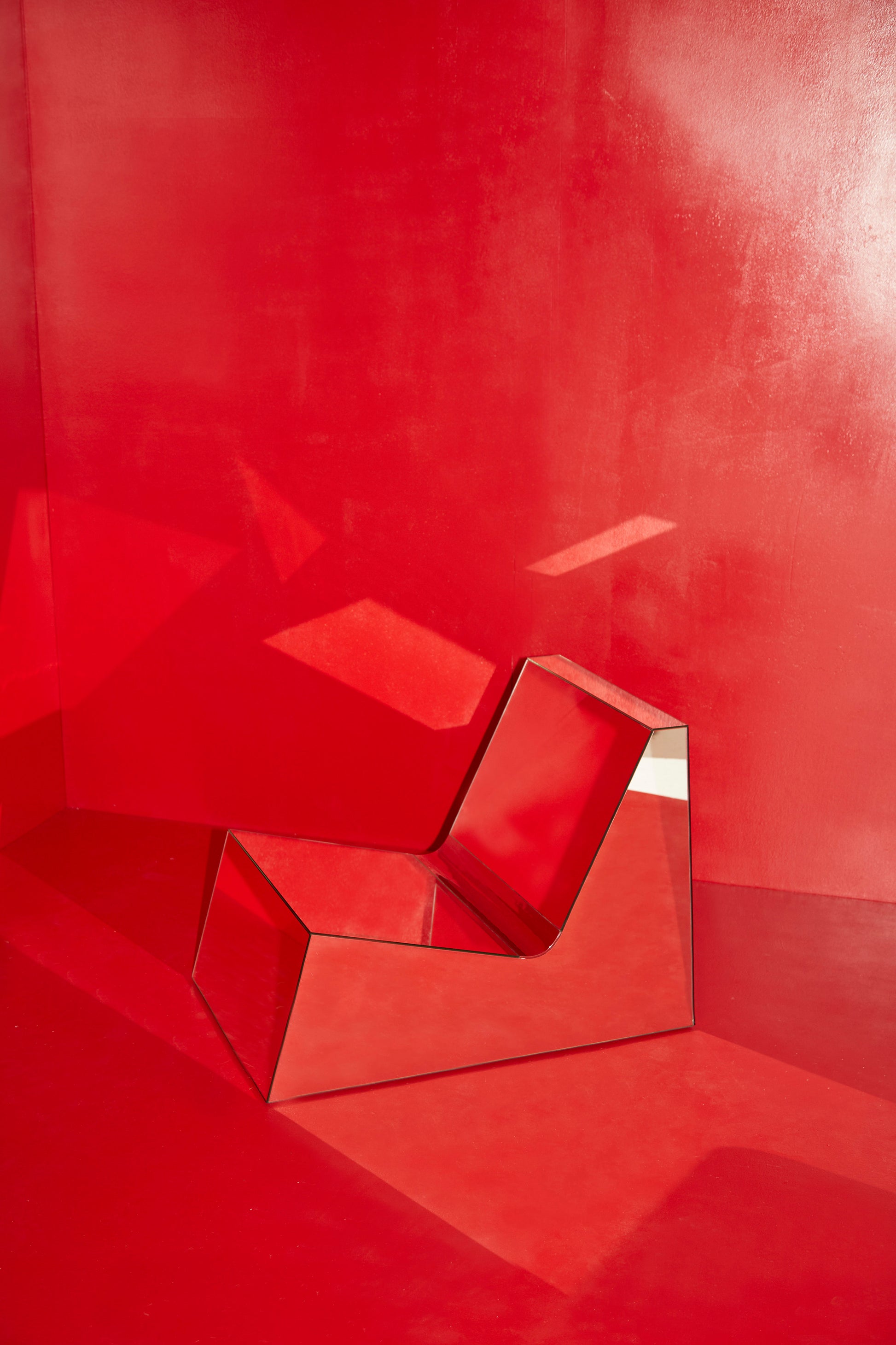 Discover a modern chair with a minimalist design, featuring a reflective mirror surface. Its angular shape creates a geometric aesthetic, set against a plain white background. This stunning piece of furniture is available for sale by The Graduate Gallery.