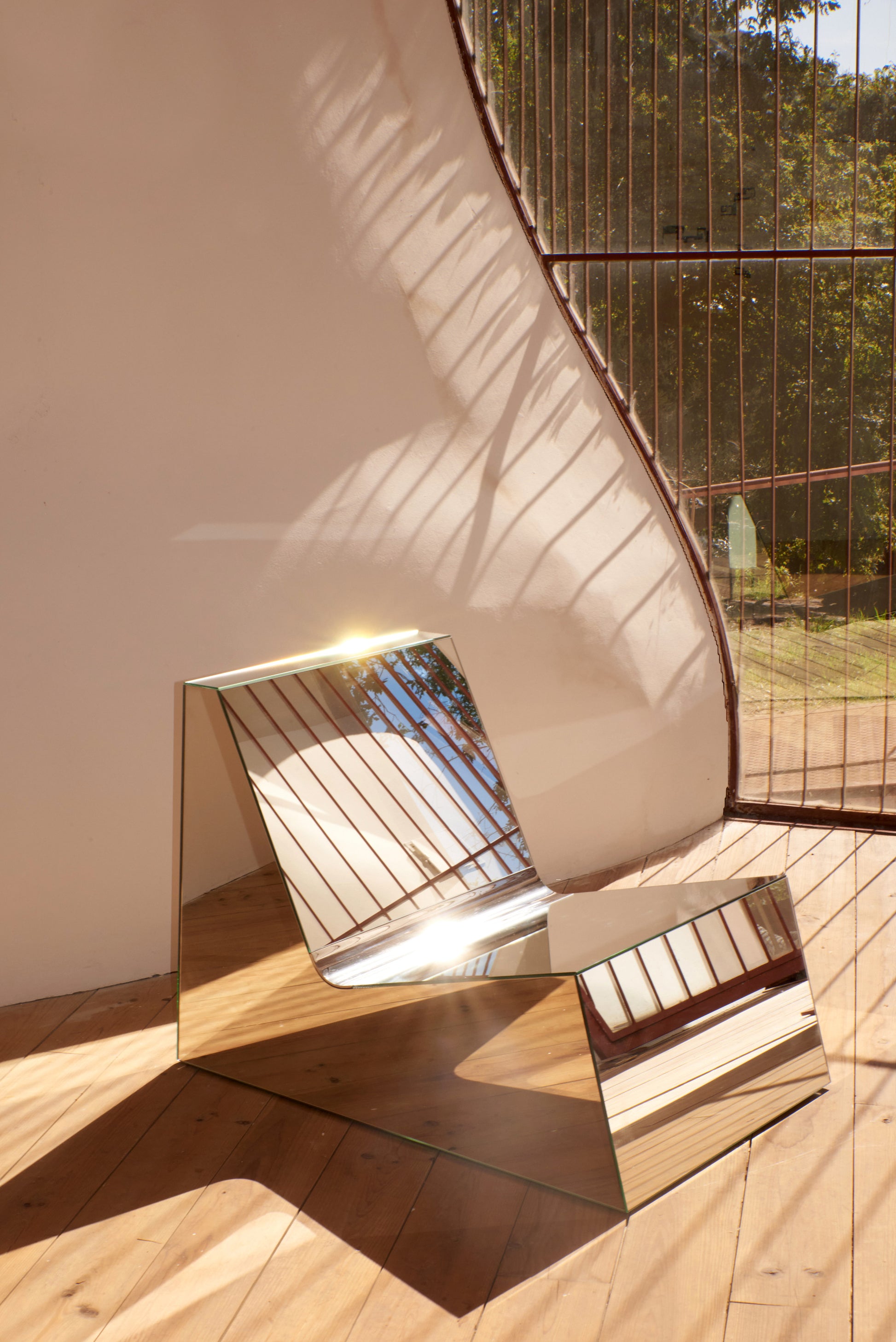 Discover a modern chair with a minimalist design, featuring a reflective mirror surface. Its angular shape creates a geometric aesthetic, set against a plain white background. This stunning piece of furniture is available for sale by The Graduate Gallery.