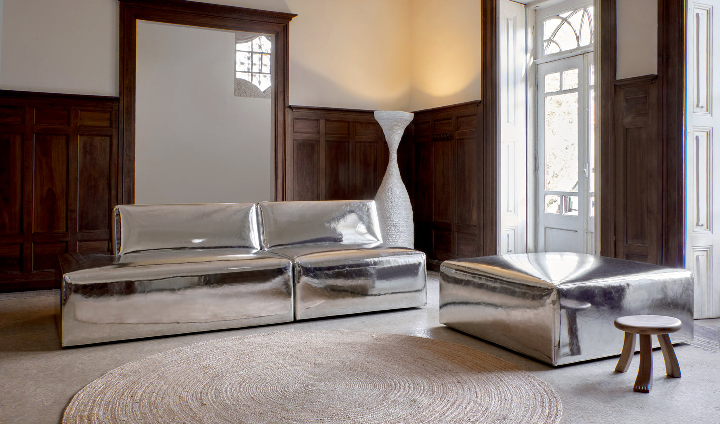 A modern, metallic couch from Project 213A a European design house launched in 2021, boasts a shiny silver finish and angular design.