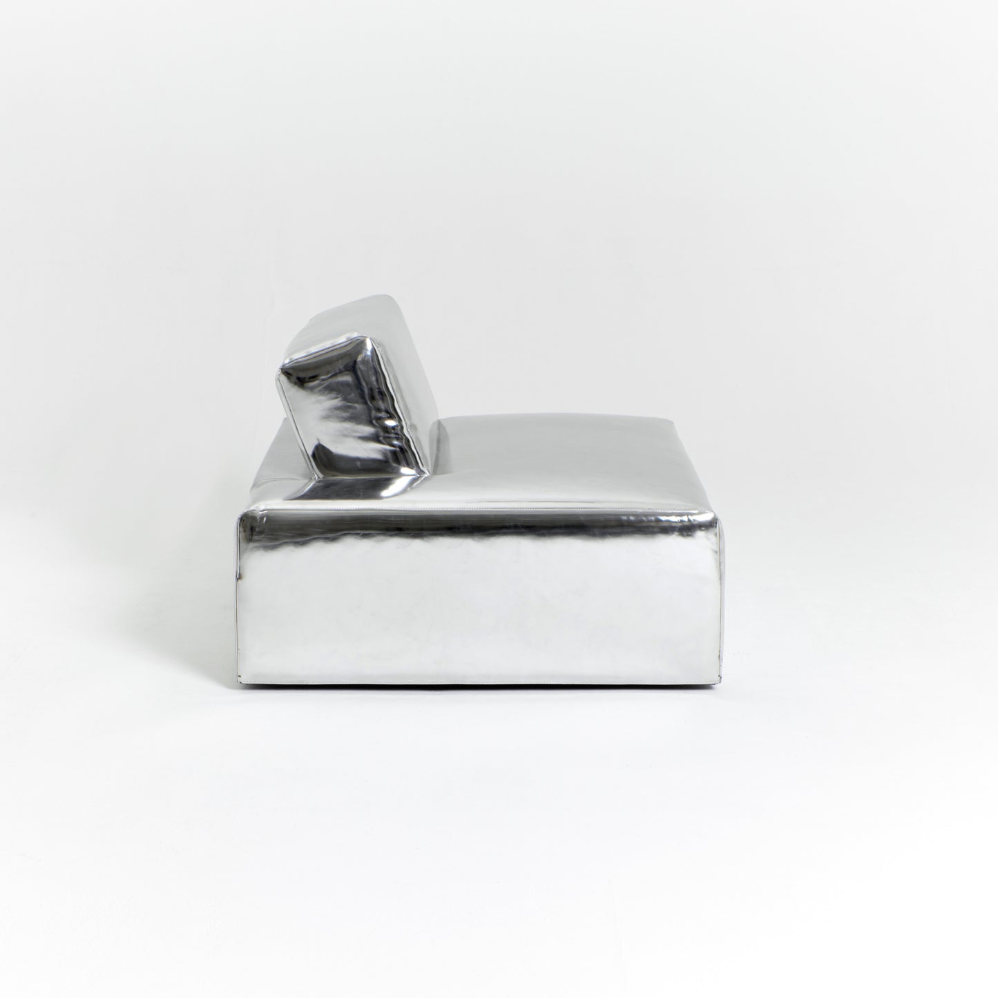 A modern, metallic couch from Project 213A a European design house launched in 2021, boasts a shiny silver finish and angular design. With its rectangular backrest, this piece of furniture stands elegantly against a plain white background.
