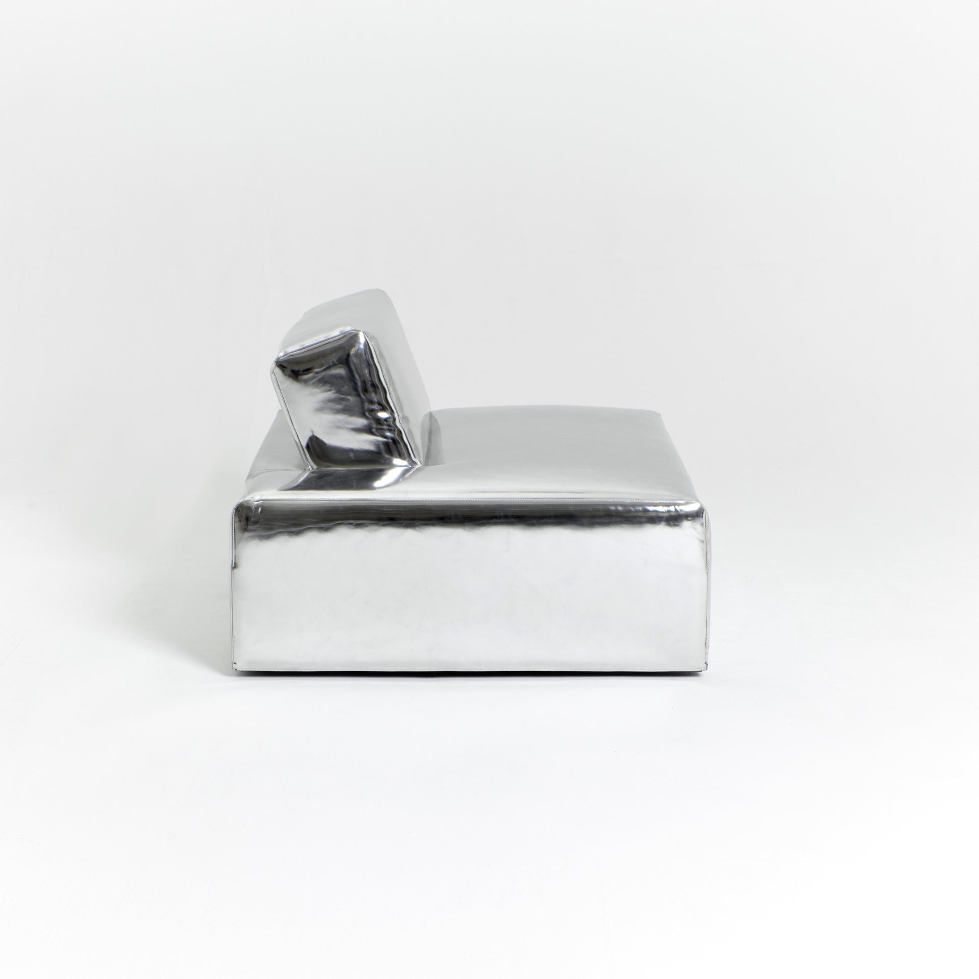 A modern, metallic couch from Project 213A a European design house launched in 2021, boasts a shiny silver finish and angular design. With its rectangular backrest, this piece of furniture stands elegantly against a plain white background.