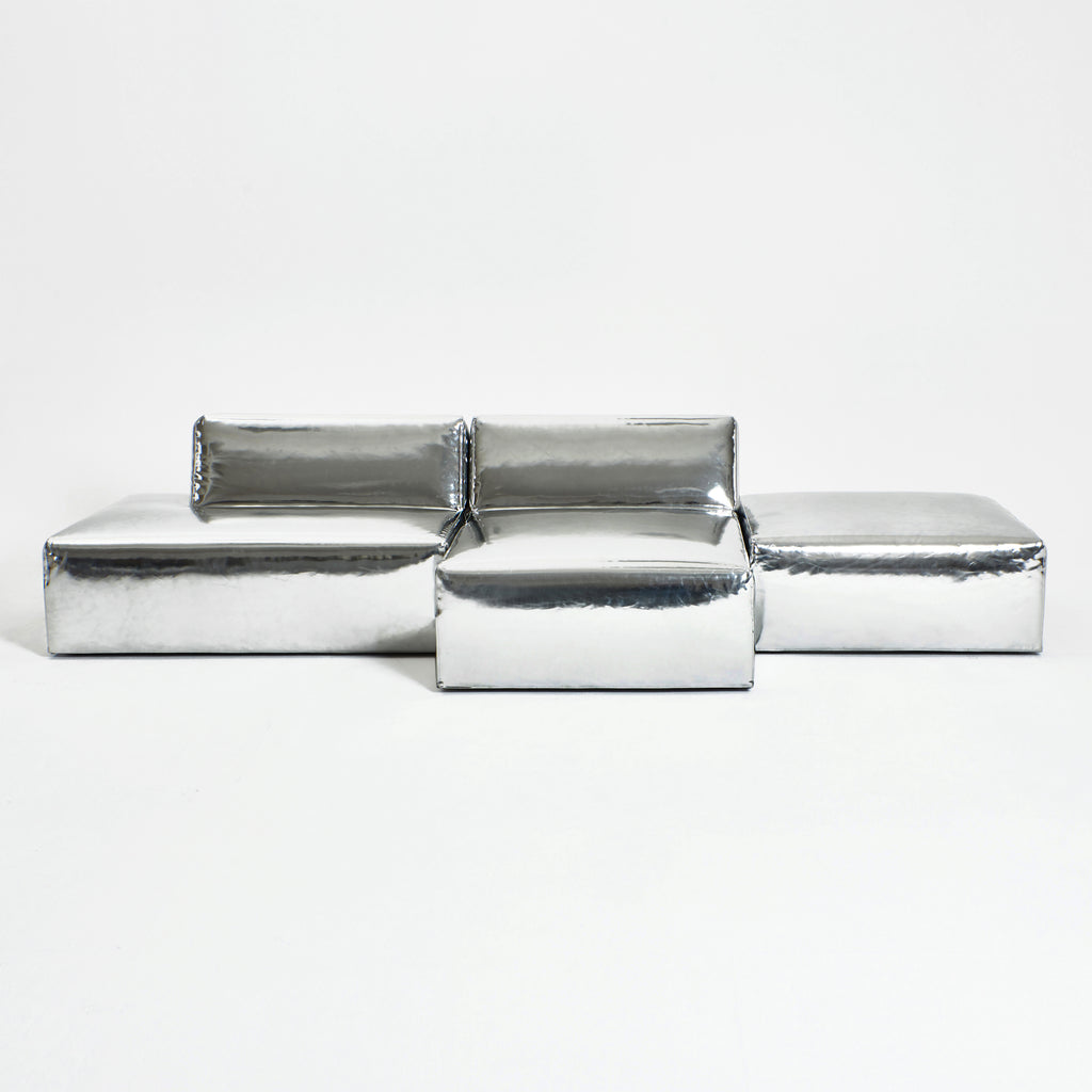 A modern, metallic couch from Project 213A a European design house launched in 2021, boasts a shiny silver finish and angular design.