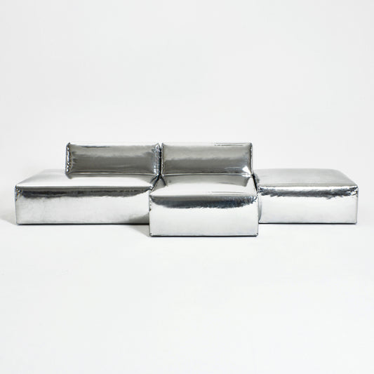A modern, metallic couch from Project 213A a European design house launched in 2021, boasts a shiny silver finish and angular design.