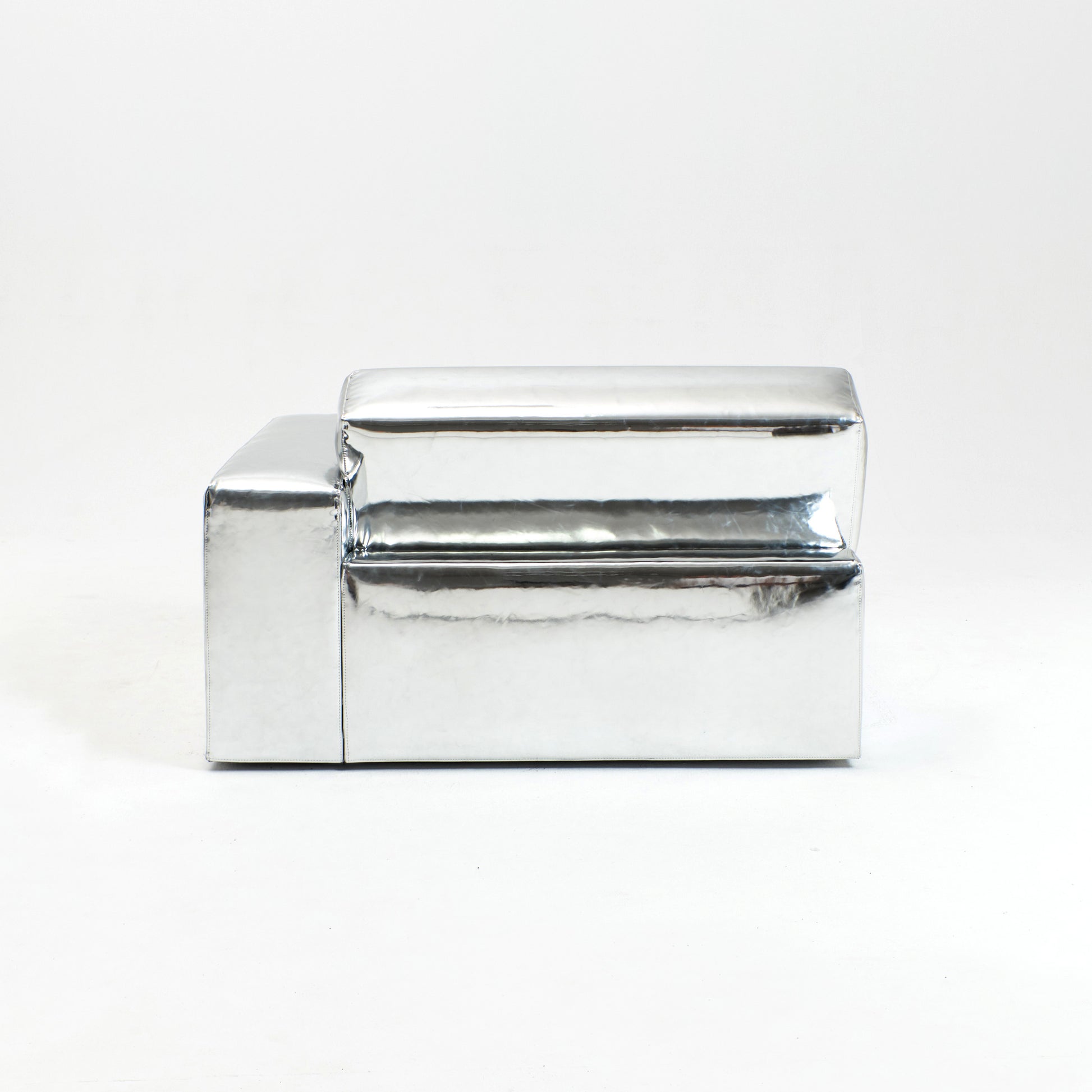 A modern, metallic couch from Project 213A a European design house launched in 2021, boasts a shiny silver finish and angular design.