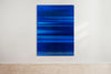 An abstract artwork by a graduate artist in the UK features horizontal bands of blue. The colors blend and blur, creating a dynamic, textured effect. Displayed with small metal clips at the corners, this piece is part of the graduate artworks for sale by The Graduate Gallery.