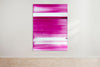 An abstract artwork by a graduate artist in the UK features horizontal bands of pink, magenta and white. The colors blend and blur, creating a dynamic, textured effect. Displayed with small metal clips at the corners, this piece is part of the graduate artworks for sale by The Graduate Gallery.