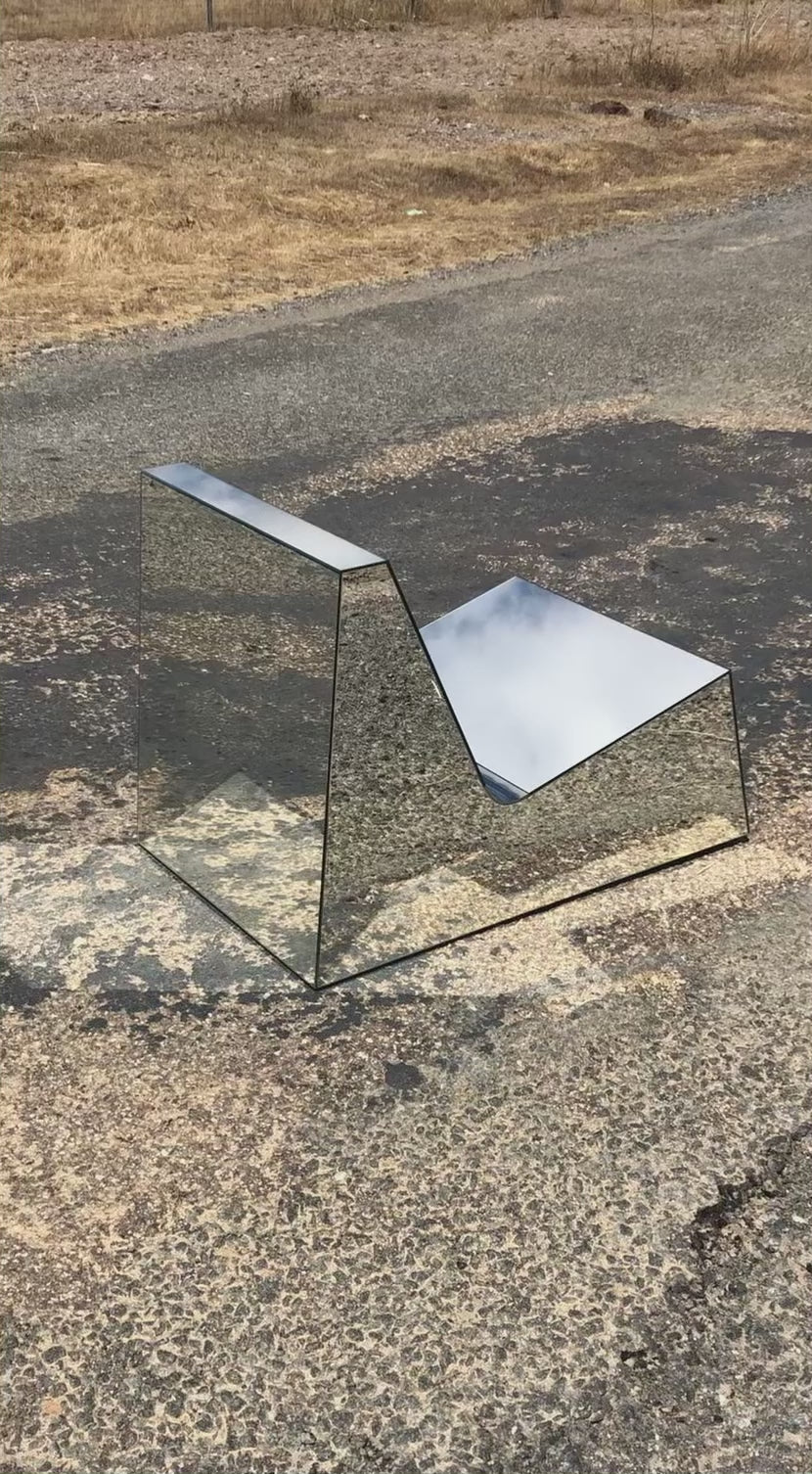 Discover a modern chair with a minimalist design, featuring a reflective mirror surface. Its angular shape creates a geometric aesthetic, set against a plain white background. This stunning piece of furniture is available for sale by The Graduate Gallery.