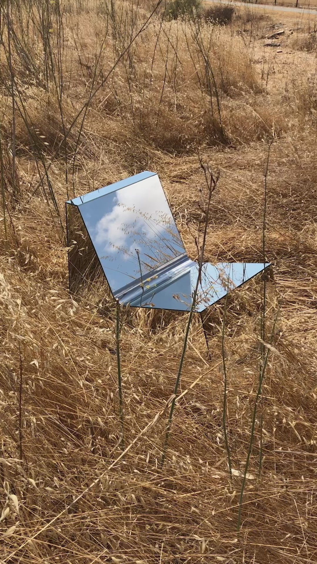 Discover a modern chair with a minimalist design, featuring a reflective mirror surface. Its angular shape creates a geometric aesthetic, set against a plain white background. This stunning piece of furniture is available for sale by The Graduate Gallery.