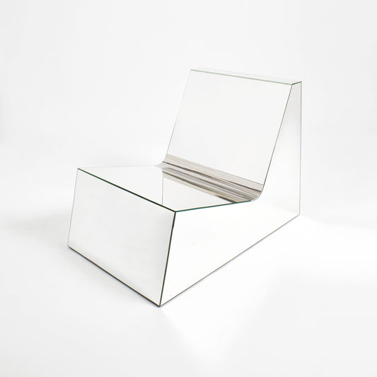 Discover a modern chair with a minimalist design, featuring a reflective mirror surface. Its angular shape creates a geometric aesthetic, set against a plain white background. This stunning piece of furniture is available for sale by The Graduate Gallery.