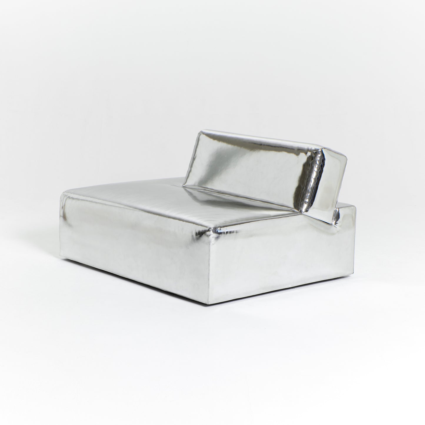 A modern, metallic couch from Project 213A a European design house launched in 2021, boasts a shiny silver finish and angular design. With its rectangular backrest, this piece of furniture stands elegantly against a plain white background.