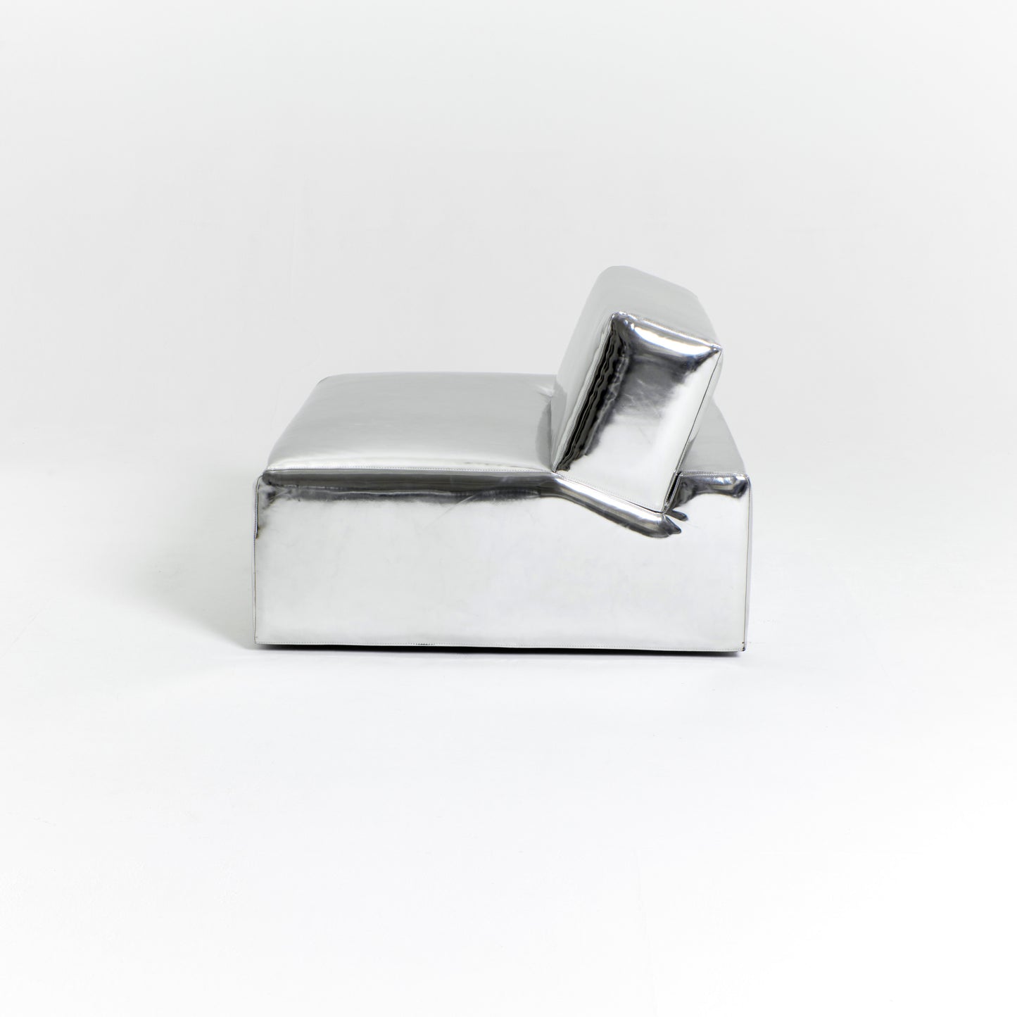 A modern, metallic couch from Project 213A a European design house launched in 2021, boasts a shiny silver finish and angular design. With its rectangular backrest, this piece of furniture stands elegantly against a plain white background.