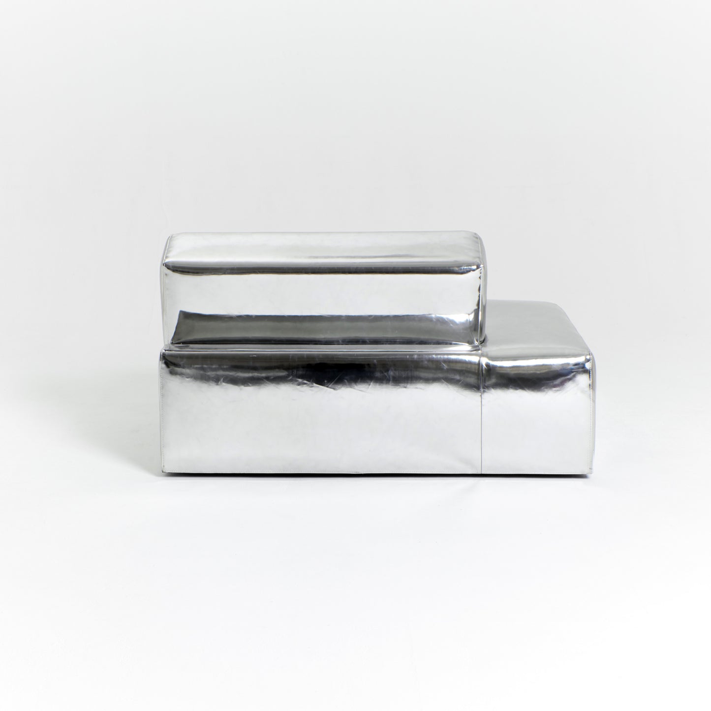 A modern, metallic couch from Project 213A a European design house launched in 2021, boasts a shiny silver finish and angular design. With its rectangular backrest, this piece of furniture stands elegantly against a plain white background.