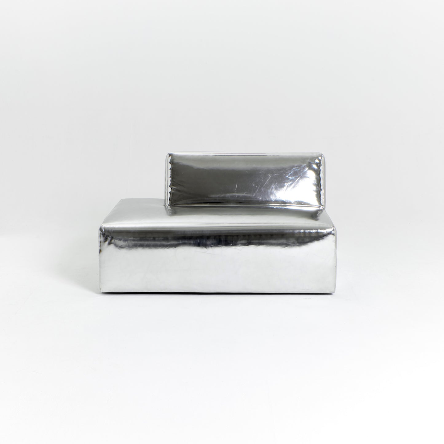 A modern, metallic couch from Project 213A a European design house launched in 2021, boasts a shiny silver finish and angular design. With its rectangular backrest, this piece of furniture stands elegantly against a plain white background.