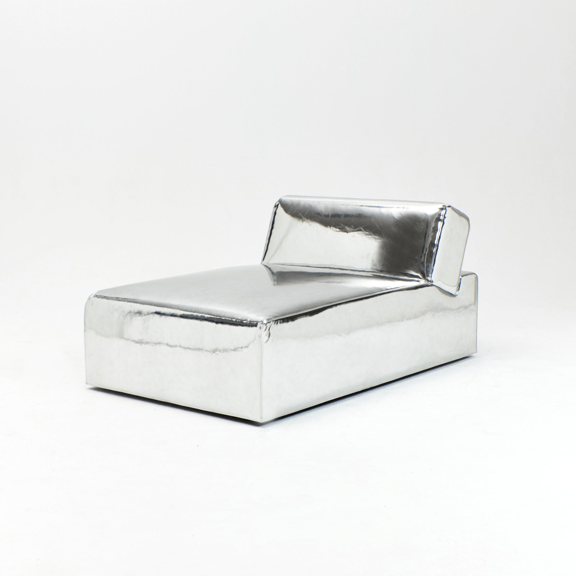 A modern, metallic couch from Project 213A a European design house launched in 2021, boasts a shiny silver finish and angular design. With its rectangular backrest, this piece of furniture stands elegantly against a plain white background.